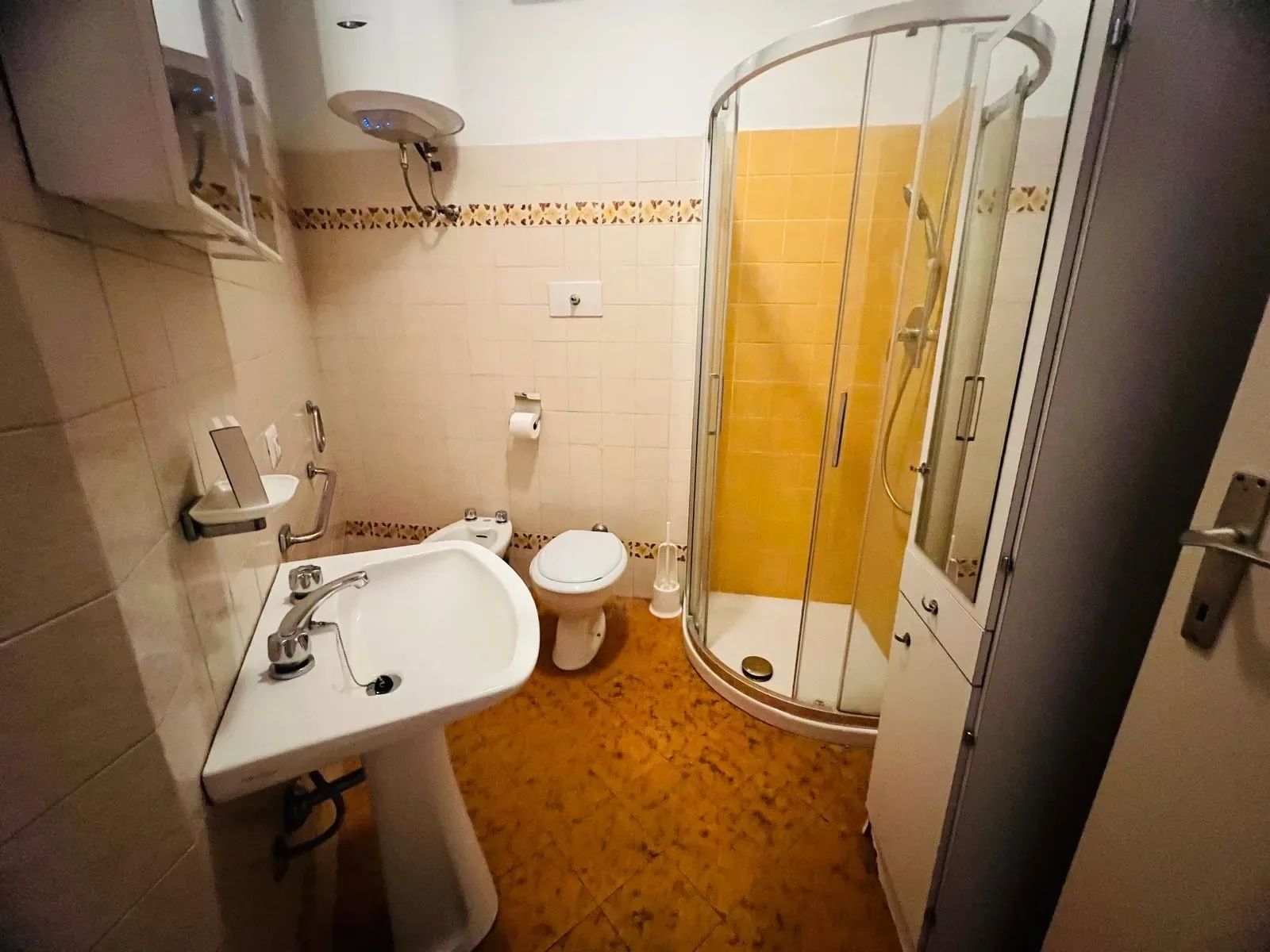 A bathroom with a sink, toilet, and shower enclosure.