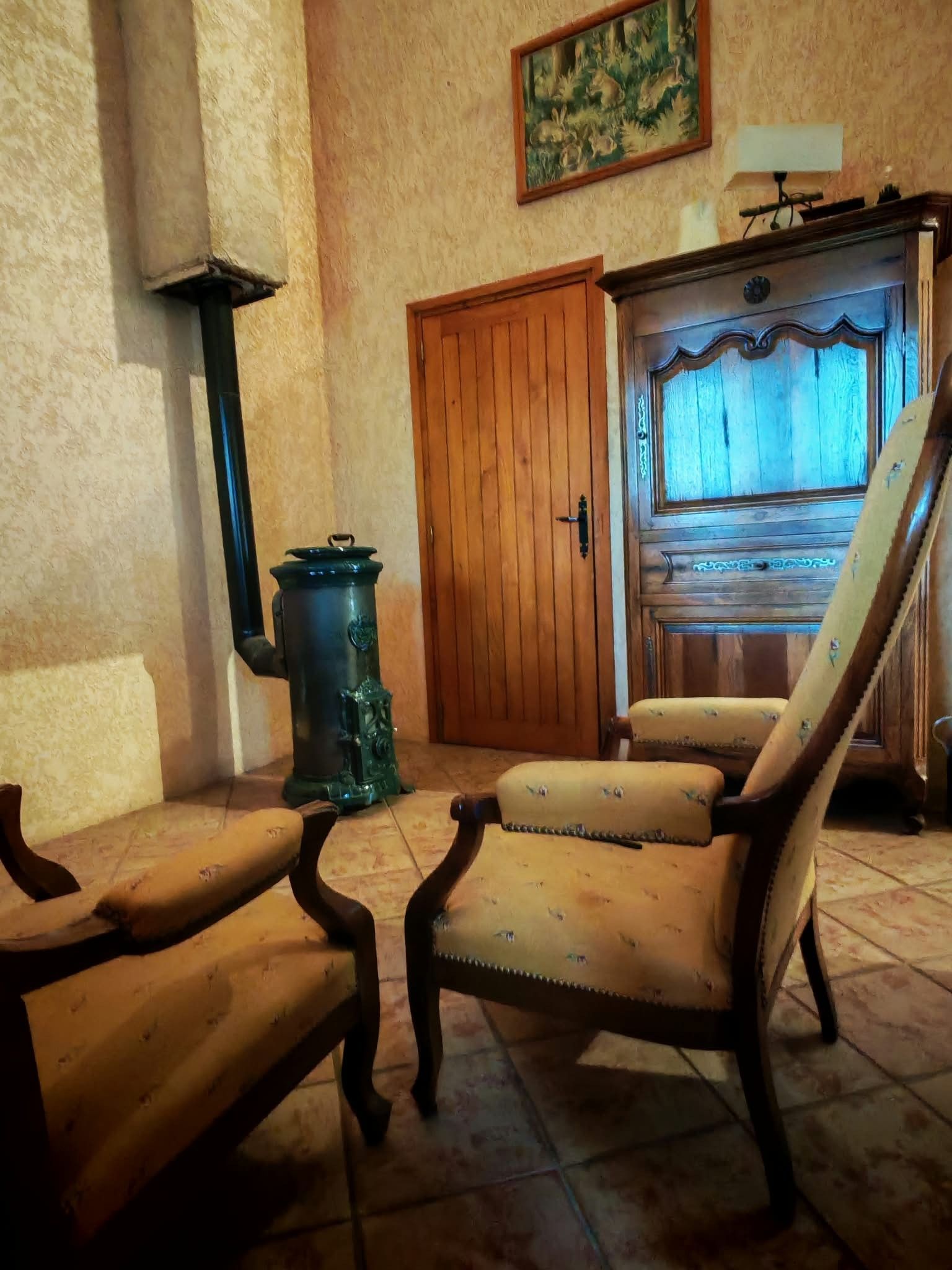 Ein Zimmer mit Holztür, einem Sessel, einem Tisch und einer Wandlampe.