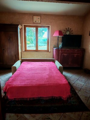 A room with a bed, a window, a television, and a cabinet.