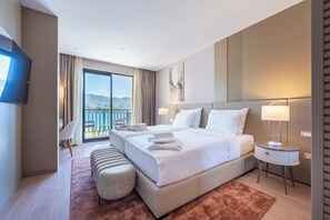 Una camera d'albergo con un letto grande, un'area salotto, una televisione e vista sull'esterno.