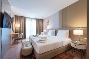 Una camera d'albergo con un letto grande, una scrivania, una sedia e una TV.