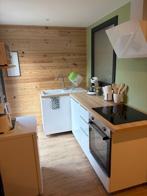 Eine kleine Küche mit Holzwand, Spüle, Herd und Arbeitsplatte mit Kochutensilien.