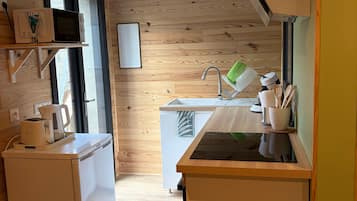 Una cocina compacta con refrigerador, microondas y pileta.