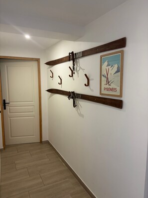 Ein Korridor mit einer Holztür, Wandbild mit Ski-Motiv und einem Holzbalken mit Haken.