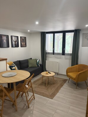 Ein modernes Wohnzimmer mit einer Couch, einem runden Esstisch, einem gelben Sessel und Kunstwerken an der Wand.
