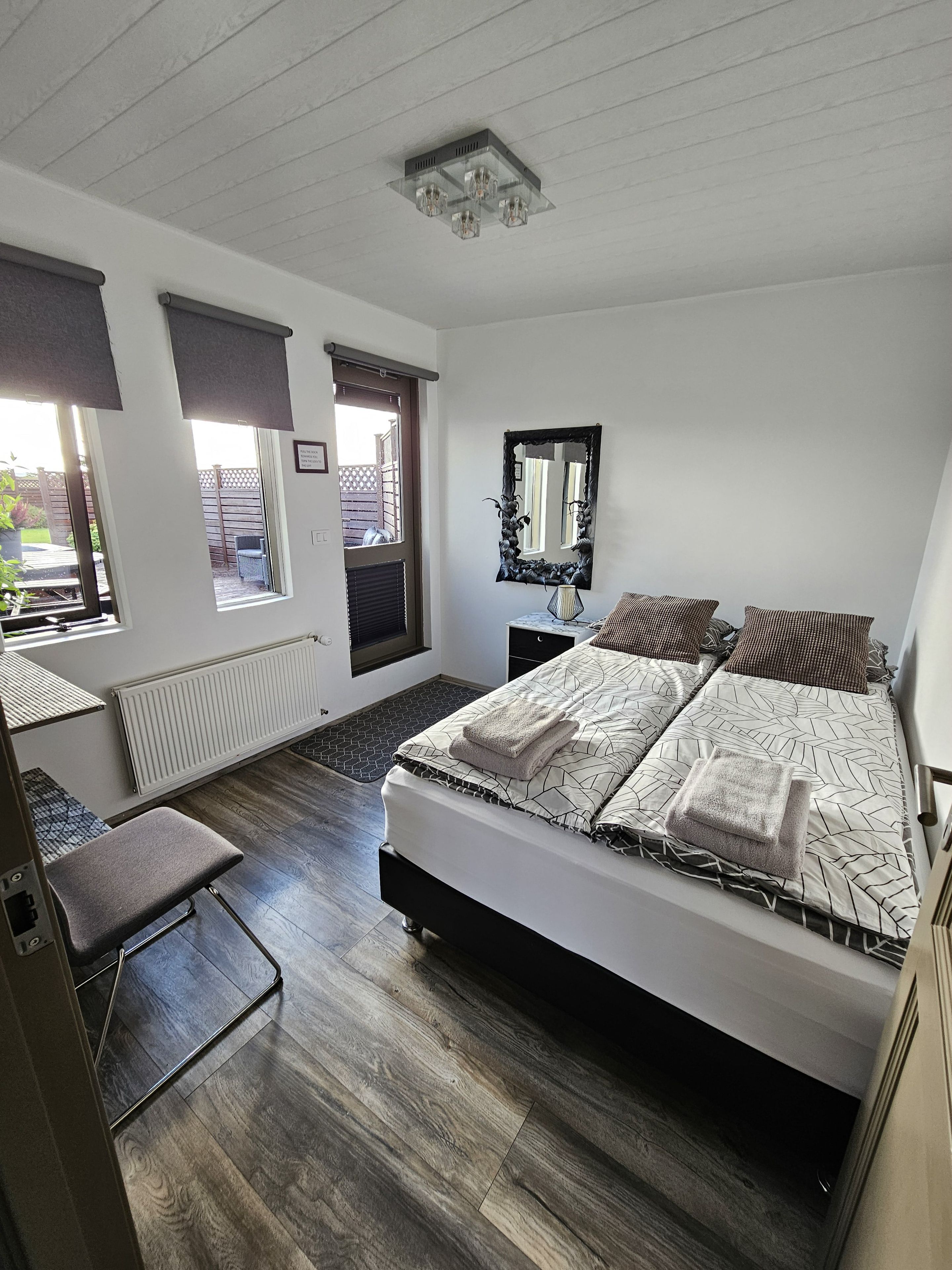 A bedroom with a bed, a chair, a radiator, and a window.