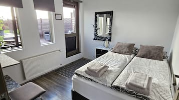 A bedroom with a bed, a chair, a radiator, and a window.