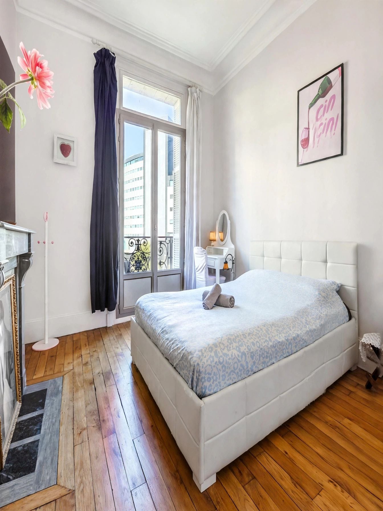 Un dormitorio con una cama grande, un aparador, un tocador con espejo y una ventana con cortinas.