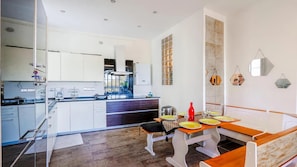 Cocina moderna con una isla central, comedor con banco y vistas al exterior.