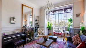 A spacious living room with a grand piano, comfortable seating, a large mirror, and a view through a tall window. - celine 40 (Alès)