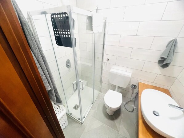 A bathroom with a glass-enclosed shower, a toilet, and a sink. - New Listing (Sanremo)