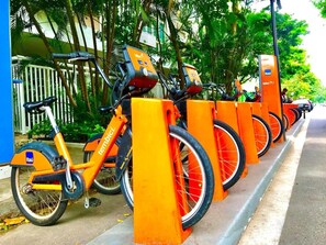 A row of orange bicycles parked at a bike-sharing station. - Praia e Conforto para 4 hóspedes (Rio de Janeiro)