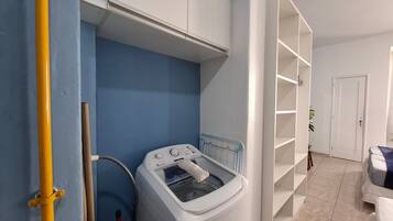 Una sala de lavandería con lavadora, tendedero y una puerta blanca.