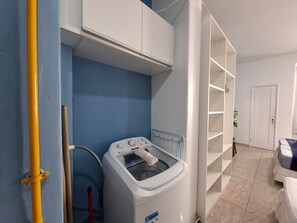 A laundry room with a washing machine, a drying rack, and a white door. - Praia e Conforto para 4 hóspedes (Rio de Janeiro)