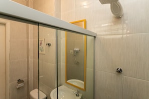 Ein modernes Badezimmer mit Duschkabine aus Glas, Toilette und Waschbecken mit Spiegel.