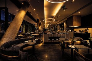 Een modern interieur met een bar, zitgedeelte en stadszicht.