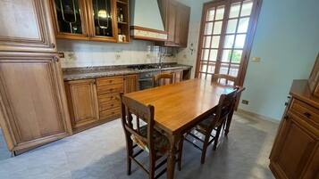 A kitchen with wooden cabinets, a granite countertop, and a dining table with chairs.
