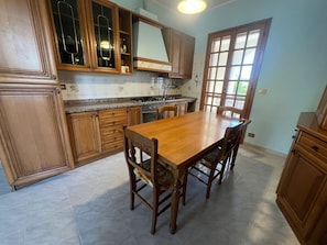 Una cocina con armarios de madera, encimera de granito y una mesa de comedor con sillas.