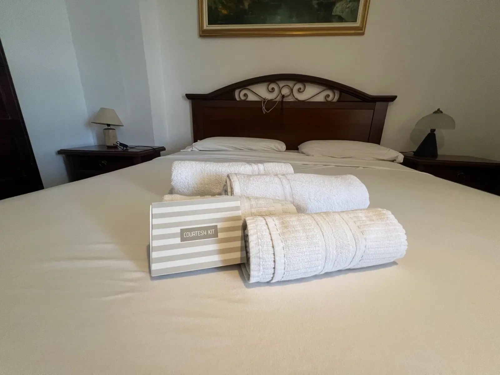 Een net opgemaakt bed met witte lakens en een gestreepte handdoekenset.