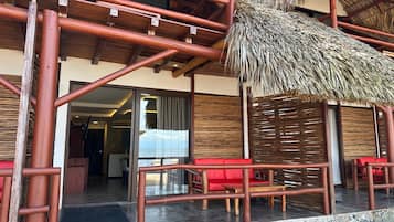 Un edificio con techo de paja, barandillas de madera y asientos rojos.