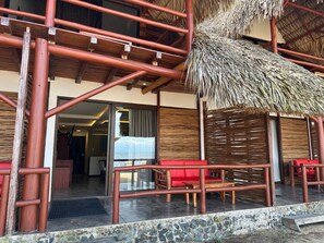 Un edificio con techo de paja, barandillas de madera y asientos rojos.
