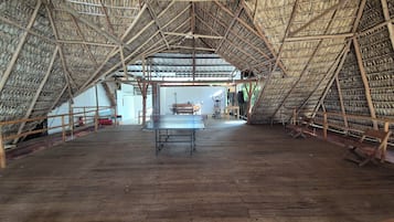 A large, open space with a high, triangular roof structure, a ping pong table, and exercise equipment.