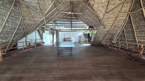 Un espacio amplio y abierto con una estructura de techo triangular alta, una mesa de ping pong y equipo de ejercicio.