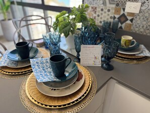 A table set with blue glassware, plates, and napkins, with a menu card visible. - Luxury Apartment Suite – Ocean View, Steps from the Beach. (Gaira)