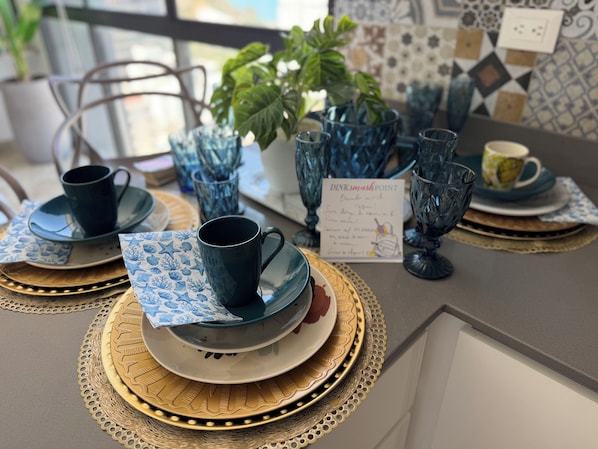 Une table dressée avec de la verrerie bleue, des assiettes et des serviettes, et un menu est visible.