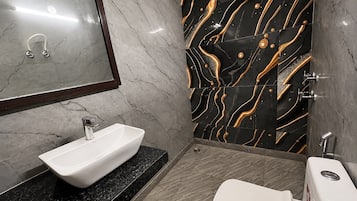 Une salle de bain avec un lavabo blanc, un miroir et des toilettes.