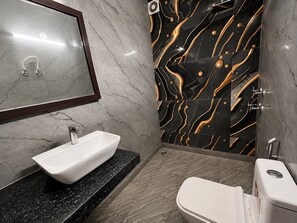 A bathroom with a white sink, a mirror, and a toilet. - Hotel Swisston Palace (New Delhi)
