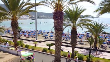 Un paseo marítimo bordeado de palmeras, con vistas al mar y gente caminando.