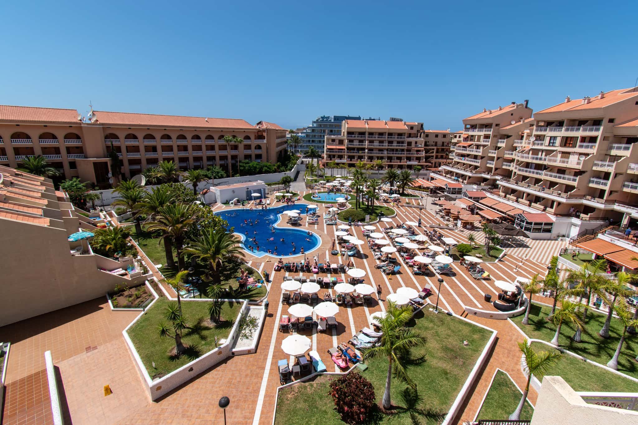 Un resort con varias piscinas, zonas de estar al aire libre y un patio central.