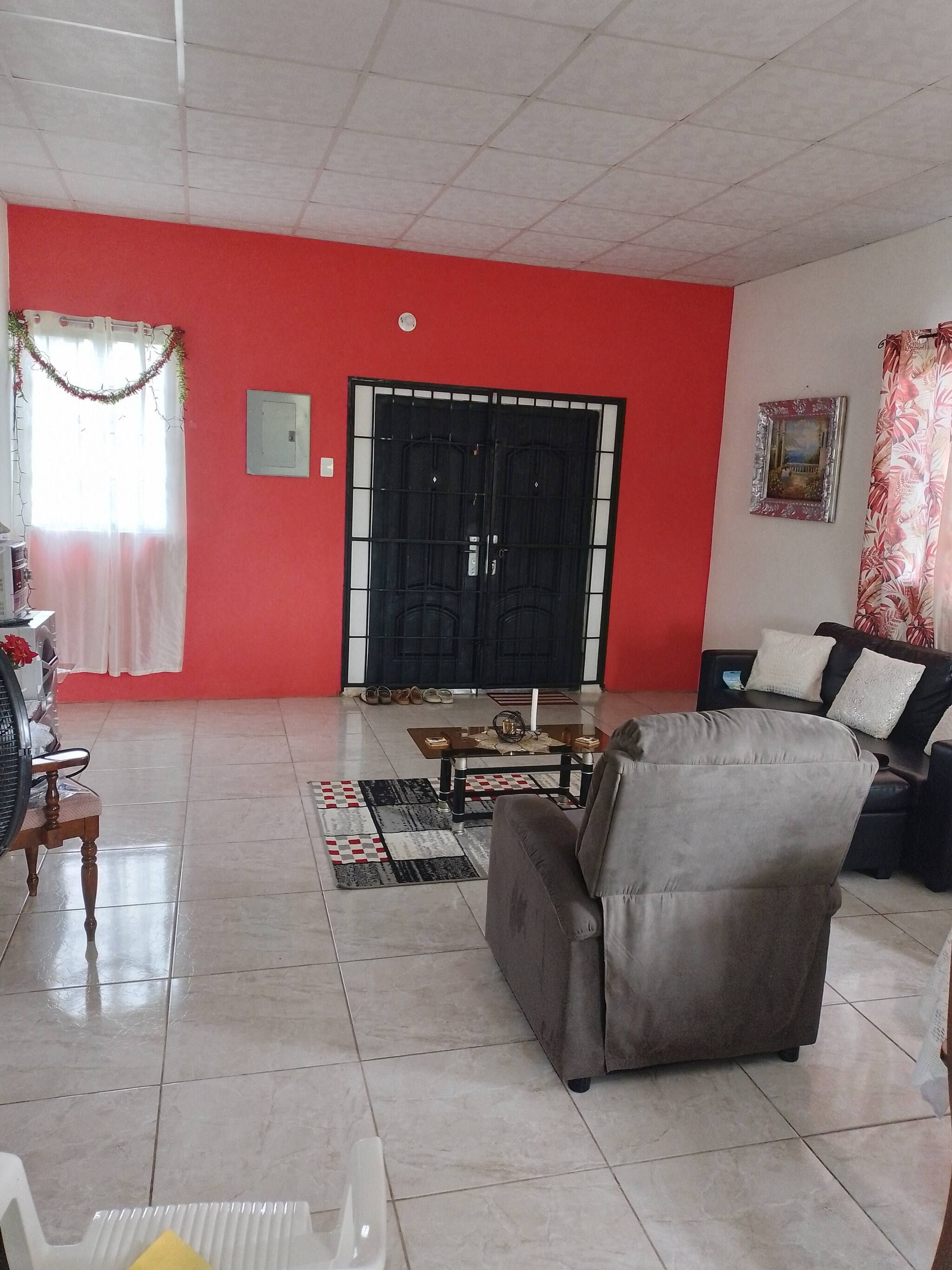A living room with a red wall, a black gate, a sofa, a coffee table, and a patterned rug.