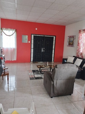 A living room with a red wall, a black gate, a sofa, a coffee table, and a patterned rug.