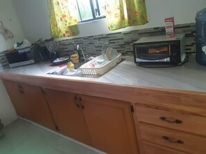 A kitchen with a microwave, toaster, and a dish rack on the counter. - Haven of Peace & Tranquility (La Brea)