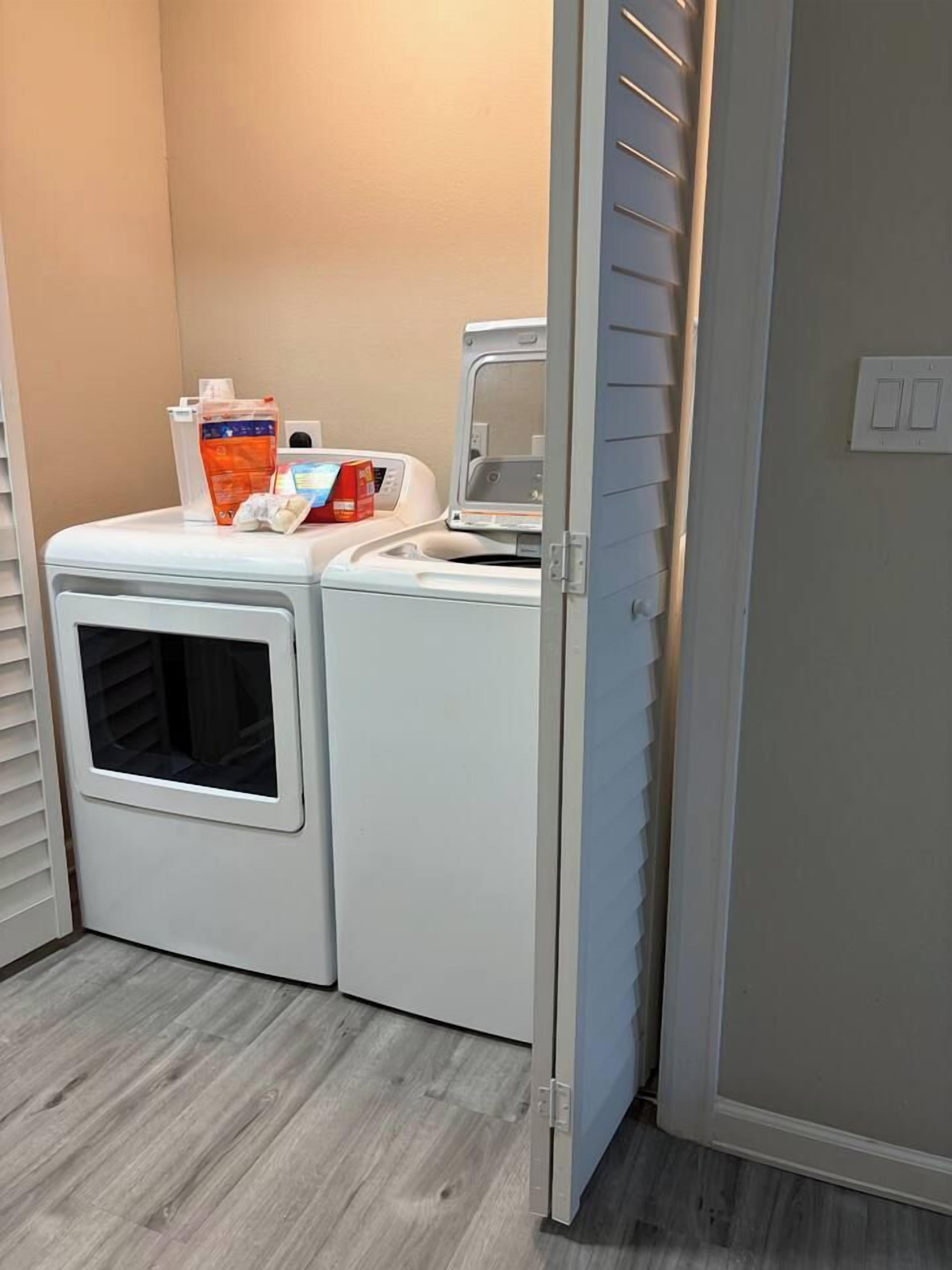 A laundry area with a dryer and washing machine, a door, and a light switch on the wall.
