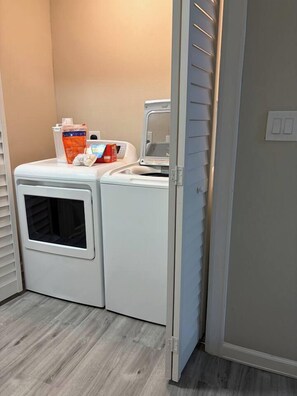 A laundry area with a dryer and washing machine, a door, and a light switch on the wall. - Remodeled 3BR-2Bath House with Deck & Carport (Morrilton)