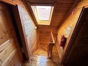 Un interior de madera con tragaluces, un extintor y una escalera.