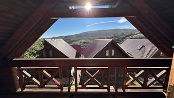 Un balcon en bois offrant une vue sur les maisons voisines et un ciel dégagé.