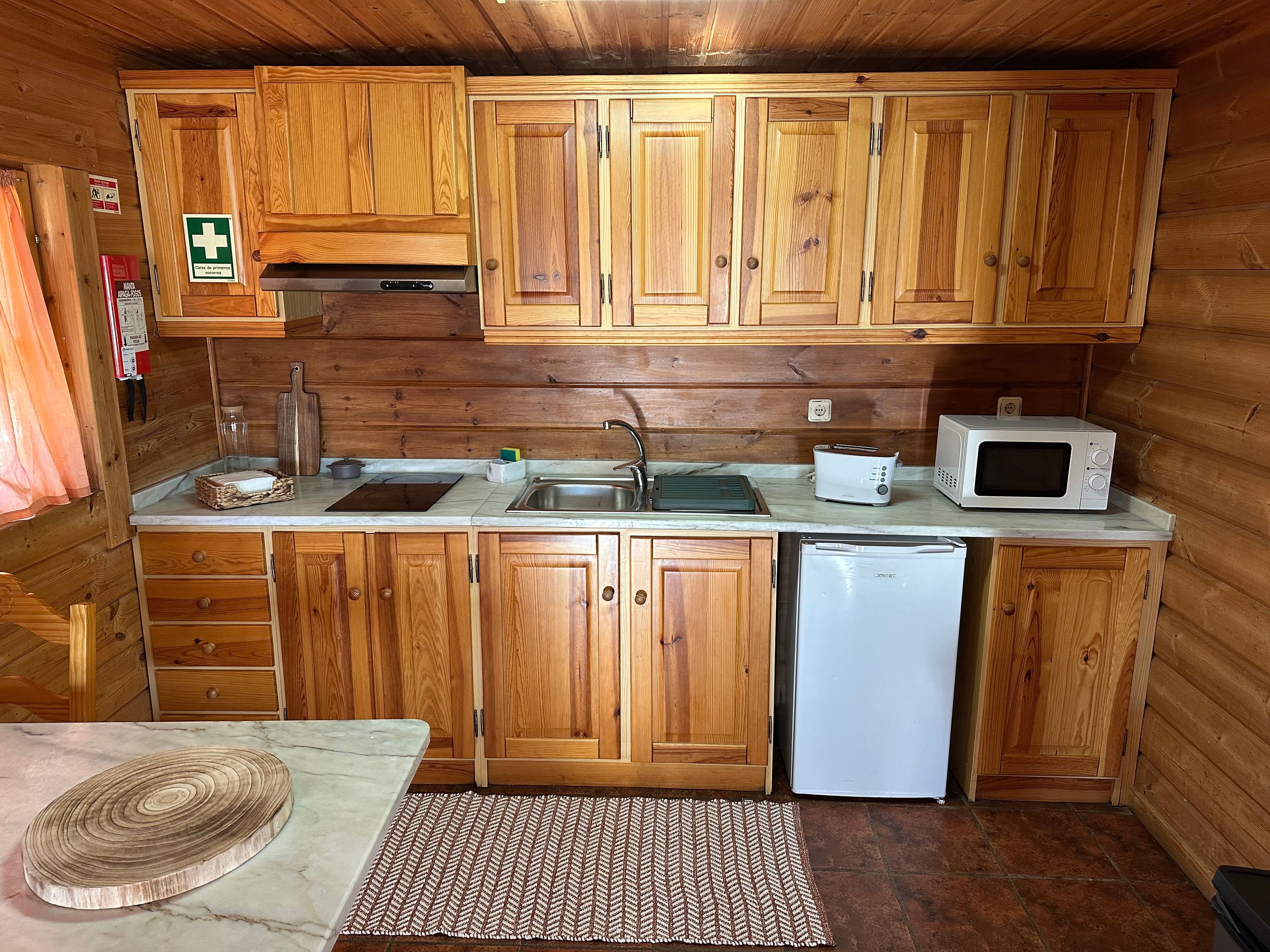 Eine kleine Küche mit Holzausstattung, einer Spüle, einem Toaster, einer Mikrowelle und einem Kühlschrank.
