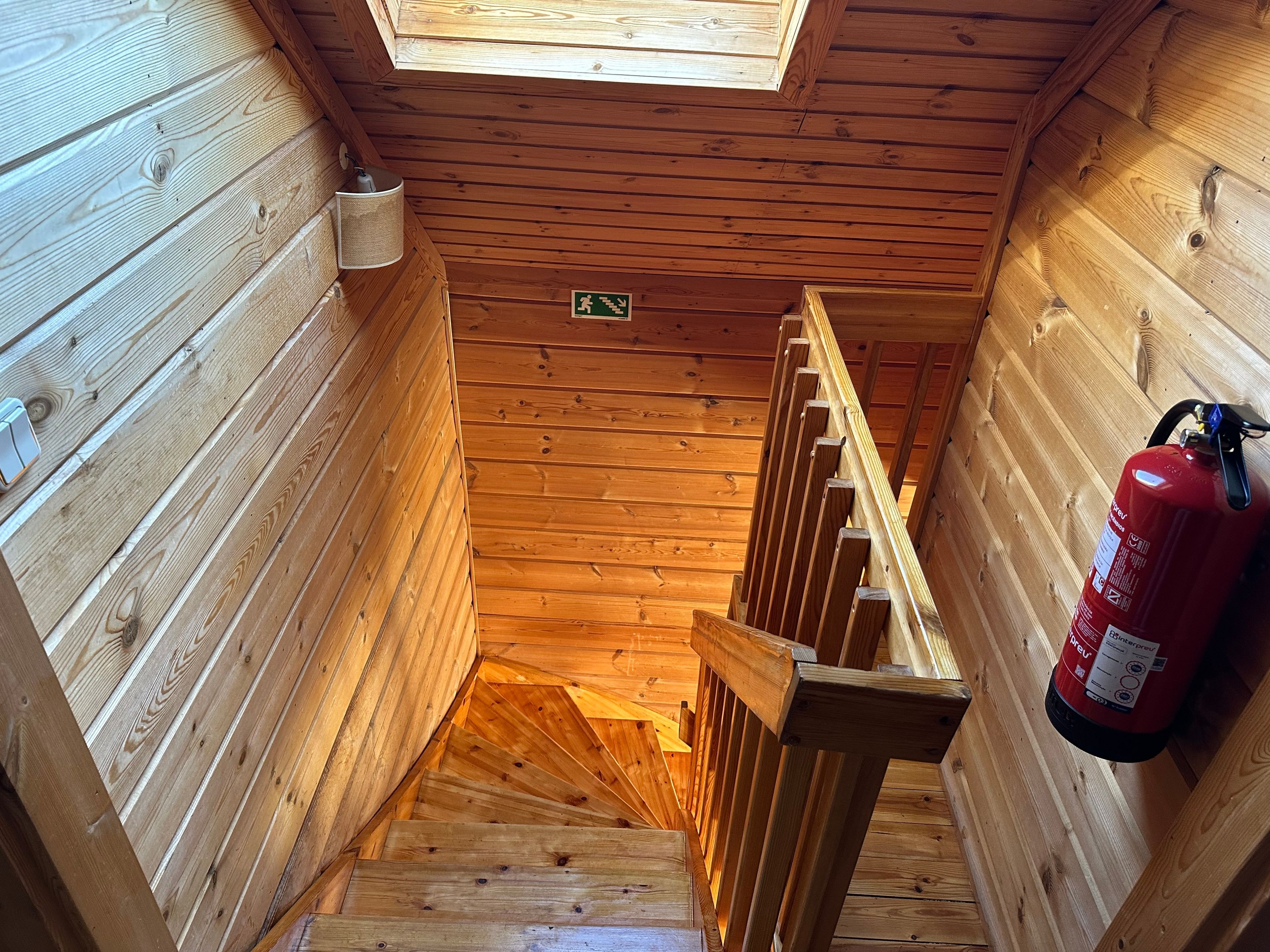 Eine Holztreppe mit einem Feuerlöscher auf der rechten Seite.