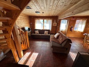 Un interior de madera con un sofá, un televisor y una escalera.