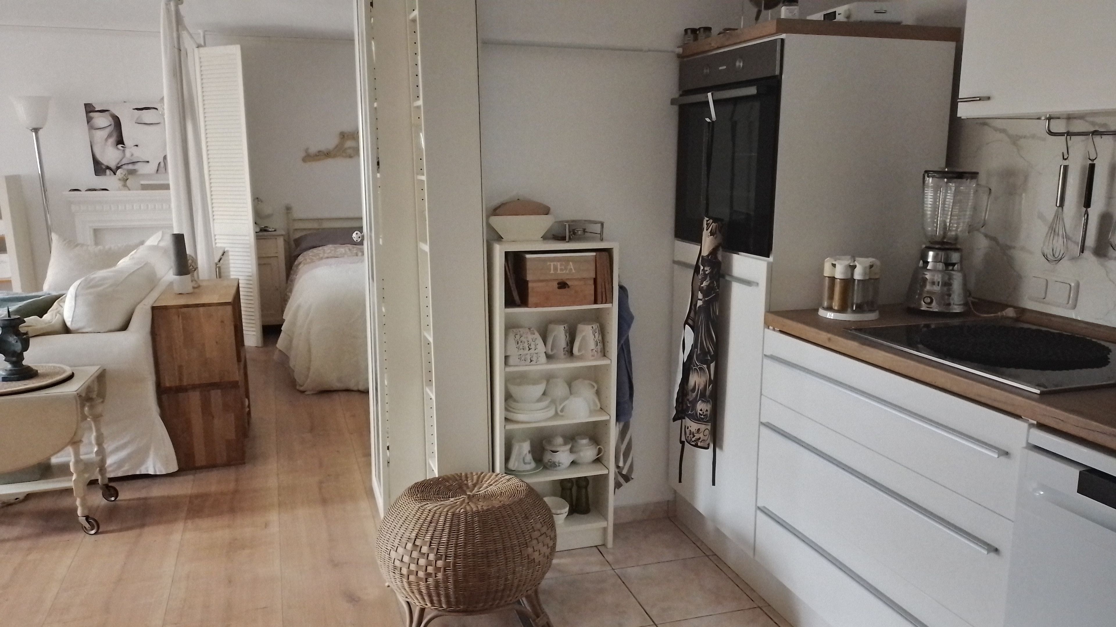 A compact kitchen with a built-in oven, a coffee machine, and a small dining area with a table and chairs.