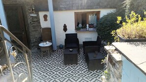 Un patio con suelo estampado, mobiliario exterior y un muro de piedra.