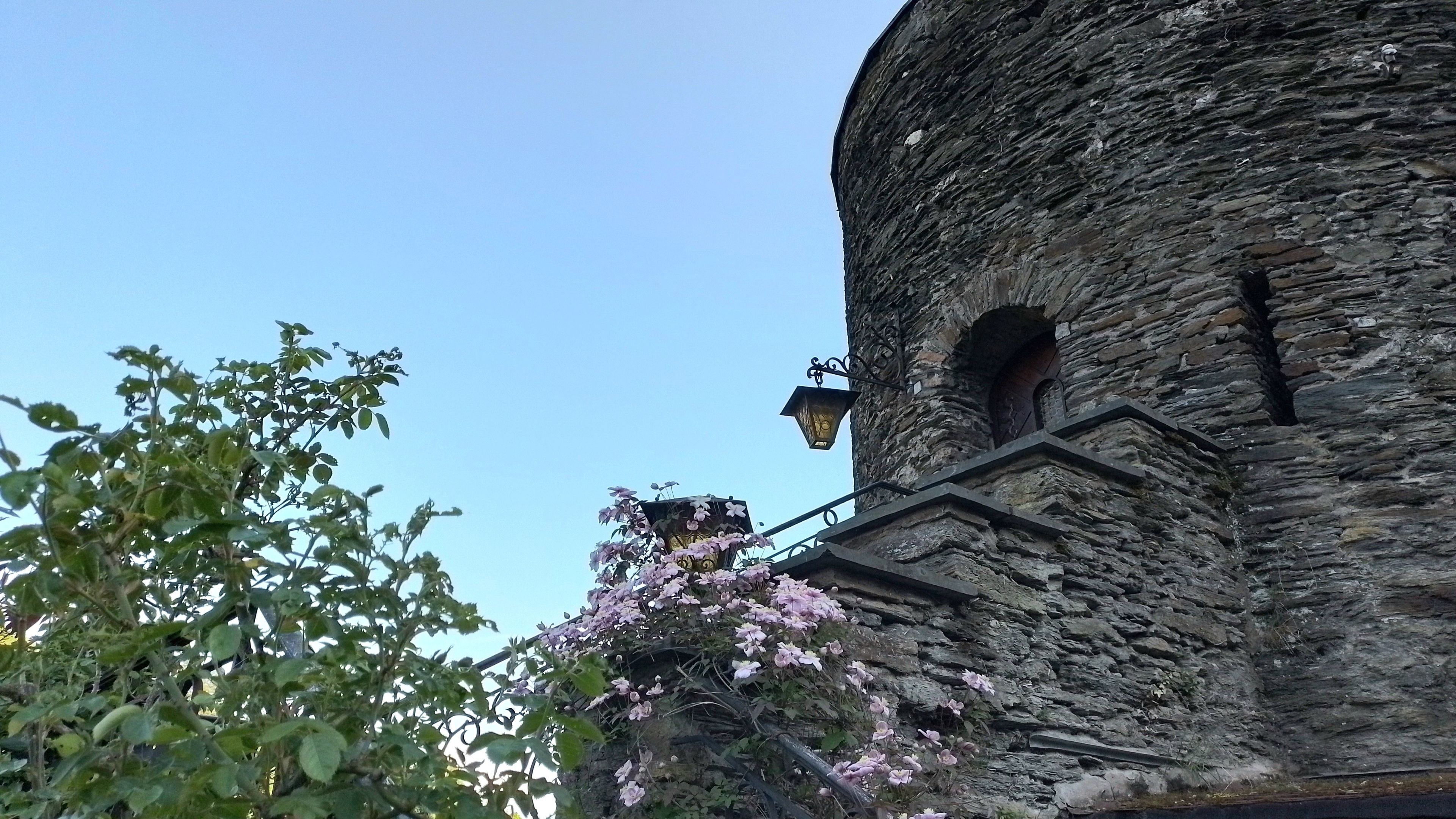 A stone building with a lantern and a flower-covered balcony.