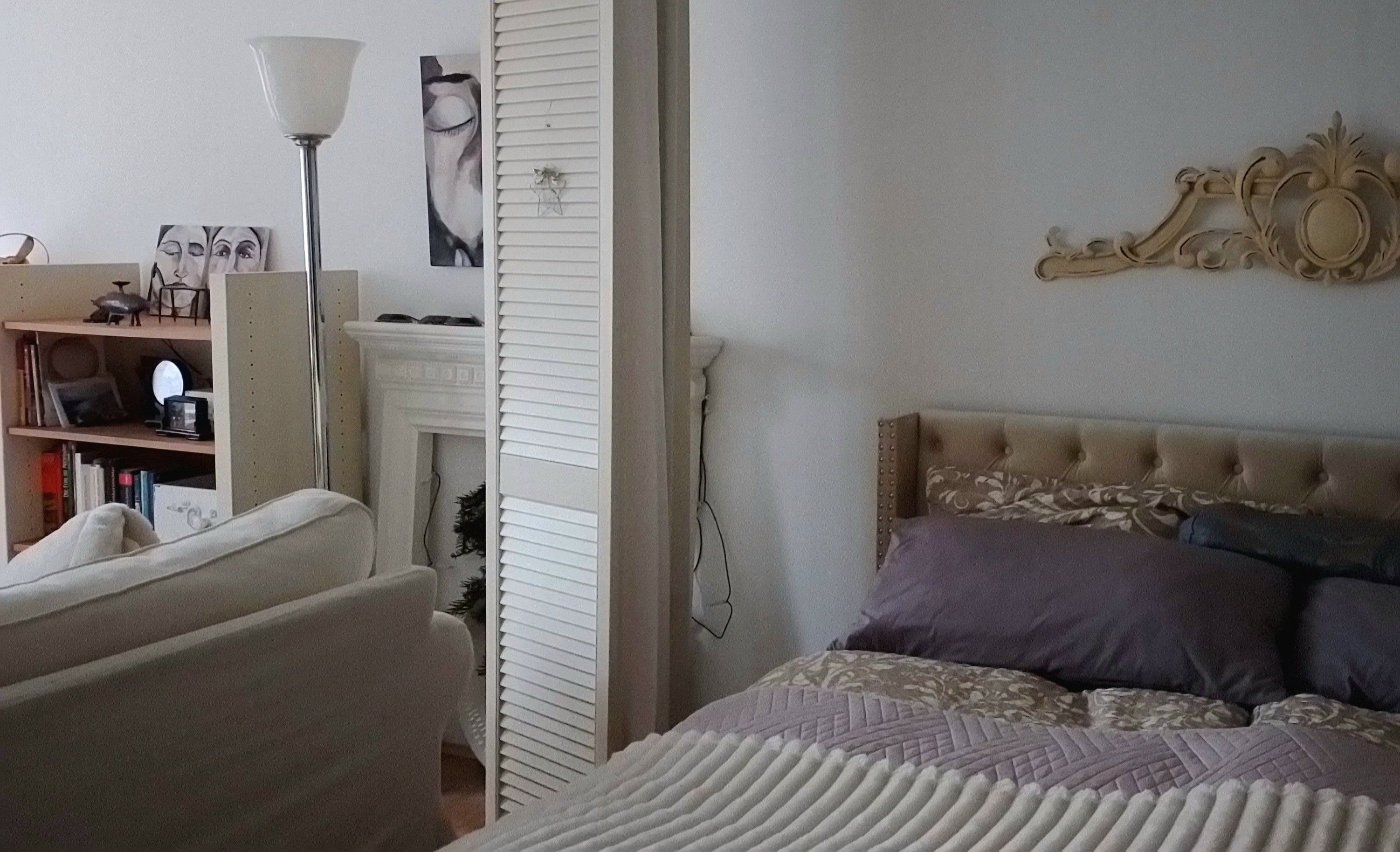 Ein Schlafzimmer mit einem Bett, einem Sessel, einem Bücherregal, einer Lampe und einem Kamin.