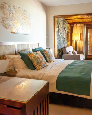 Une chambre d’hôtel comprenant un lit, un coin salon avec un fauteuil et un élément décoratif mural.