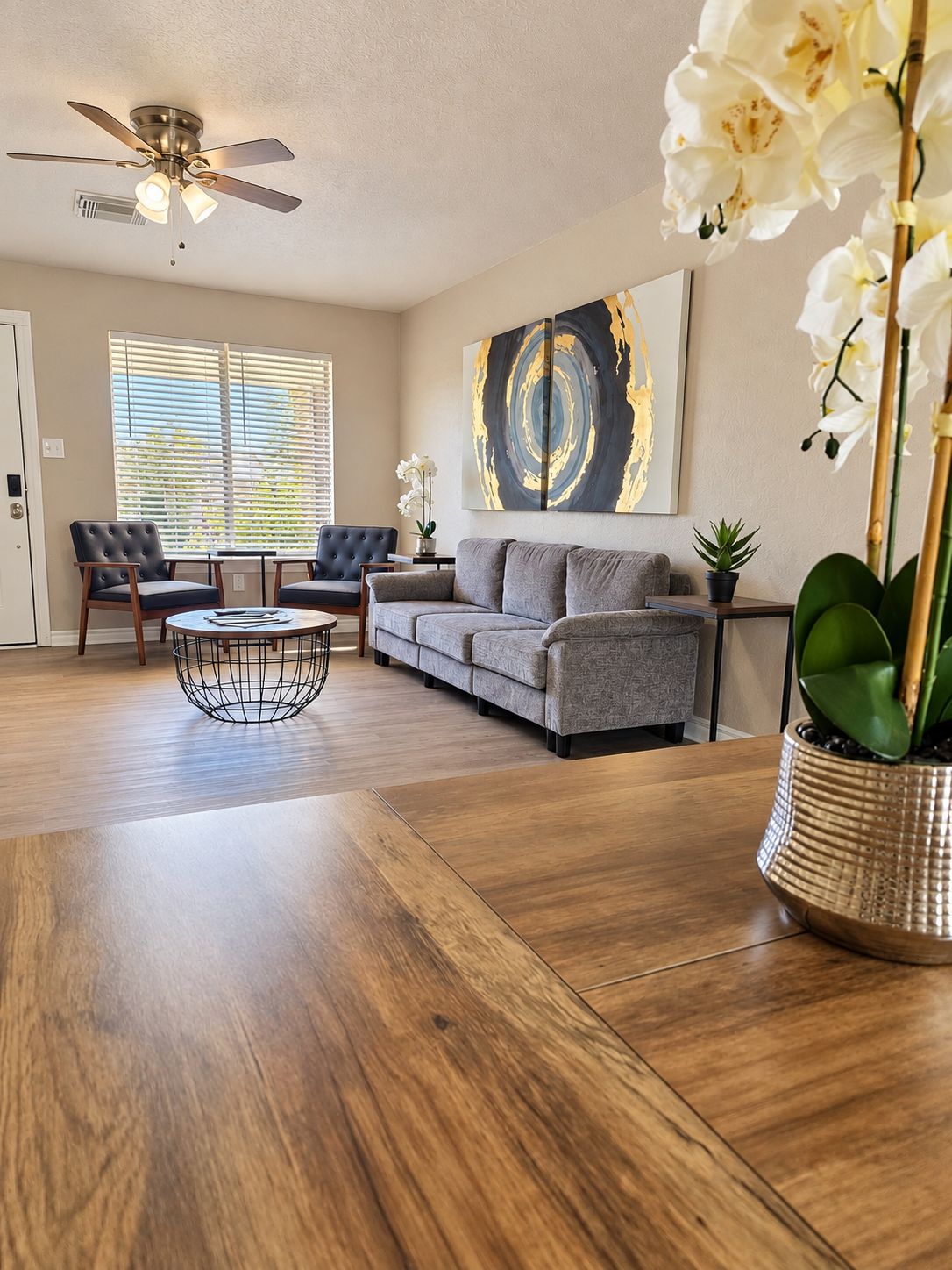 A living room with a sofa, two chairs, a coffee table, and a ceiling fan.