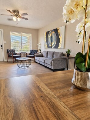 Ein Wohnzimmer mit einer Couch, zwei Sesseln, einem Couchtisch und einem Deckenventilator.